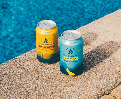 Two cans of beer next to a pool.